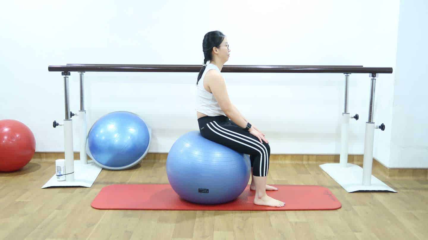 A clinical pilates instructor shows the starting position of seated pelvic tilts - useful for treating Scoliosis in Children.